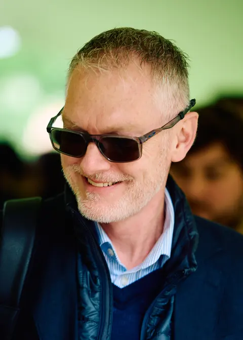 A guest in sunglasses and a navy jacket smiling