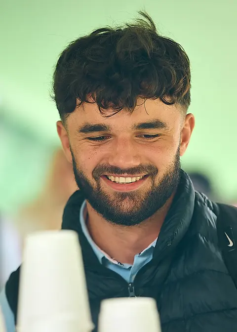 A bearded guest smiling while holding two coffee cups