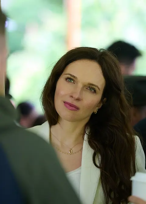 A guest in a white coat and a gold necklace