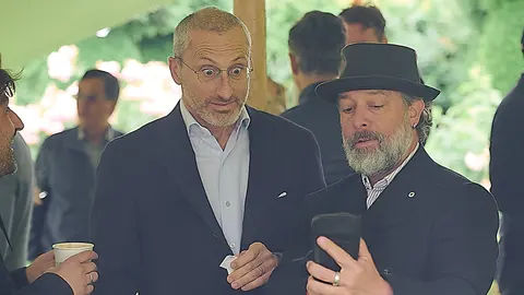 Two guests talking, one checking his phone