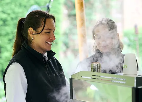 A barista steaming milk at the coffee cart
