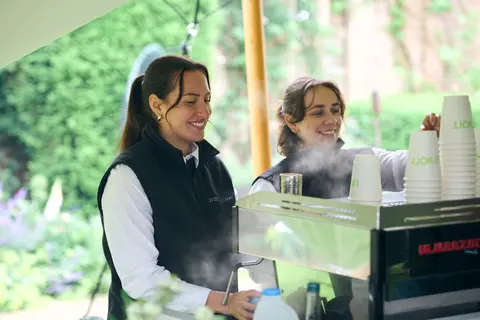 Baristas making coffee at a cart in the marquee