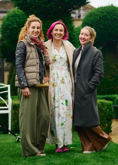 Three guests posing under a rose covered archway