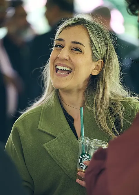 A guest laughing with a coffee cup in her hand
