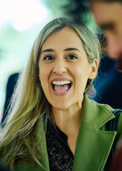 A guest laughing broadly in a green coat