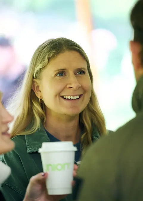 A guest holding a coffee cup mid conversation