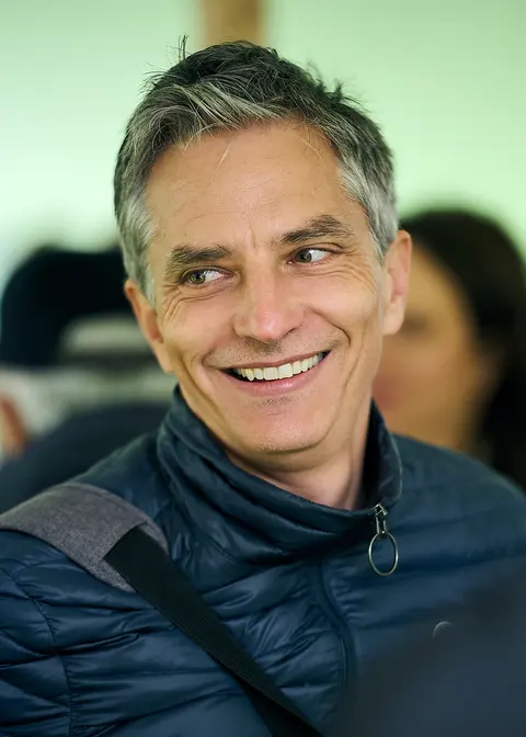 A grey haired guest in glasses, smiling