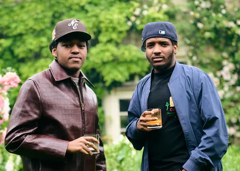 Two young guests in caps holding drinks in the garden