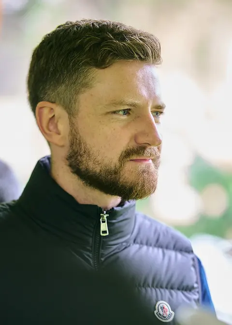 A guest with a red beard in a gilet, in profile