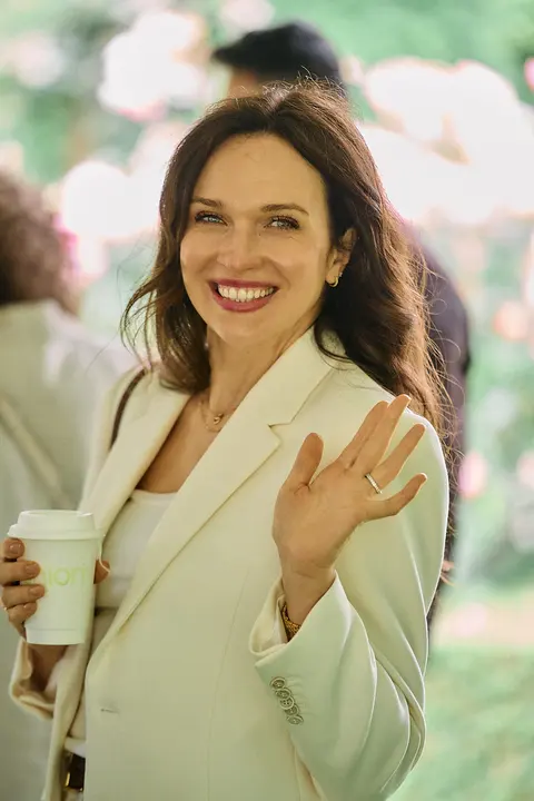 A guest in a cream blazer waving