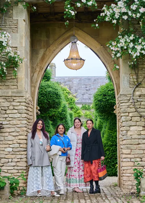Guests standing under a stone arch hung with roses and a lantern