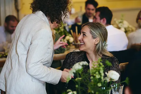 A guest in a cream blazer talking at the table