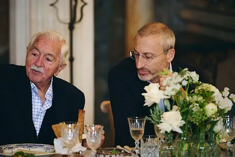 Two older guests in conversation at dinner