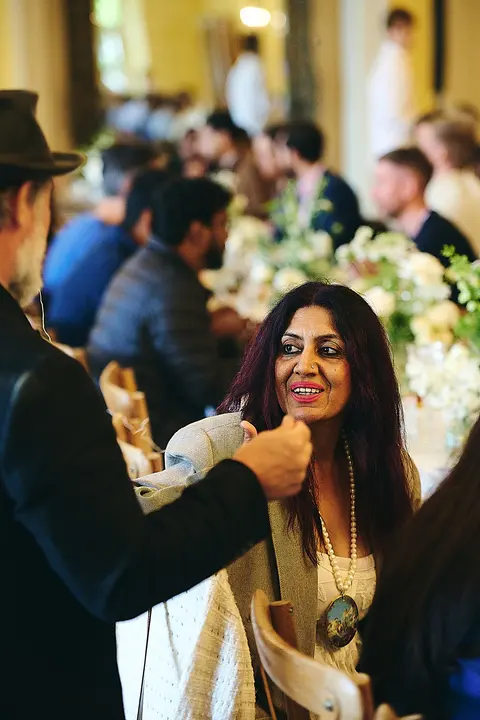 A guest adjusting a friend's collar at the table