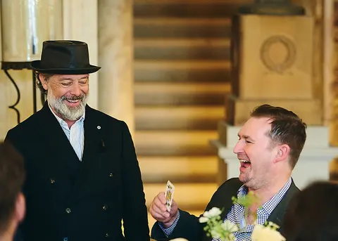 A guest in a hat laughing with a younger guest