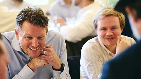 Two guests laughing together, hands clasped at the table