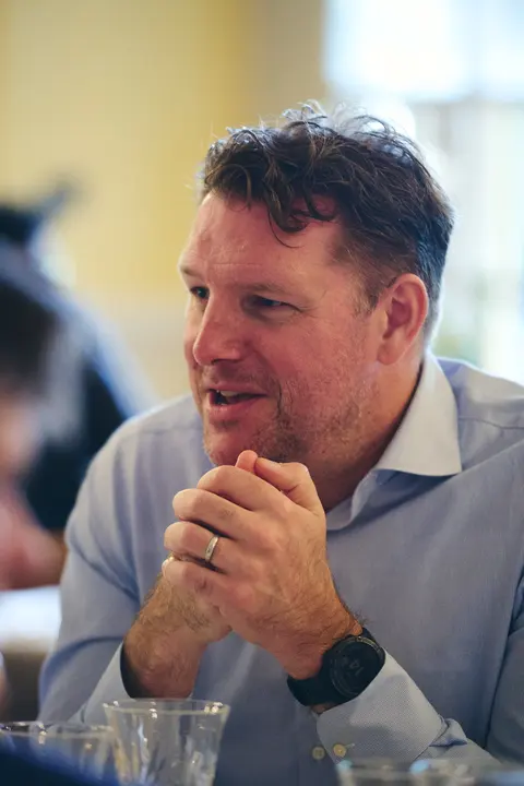 A guest in a dark jacket smiling at the table