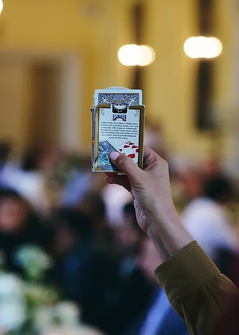 A guest holding up a playing card at the table