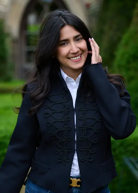 A guest smiling and brushing back her hair among the topiary