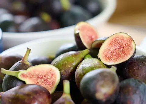 A bowl of ripe figs, some halved