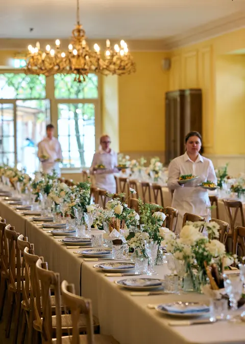 Staff setting a long table with white flowers