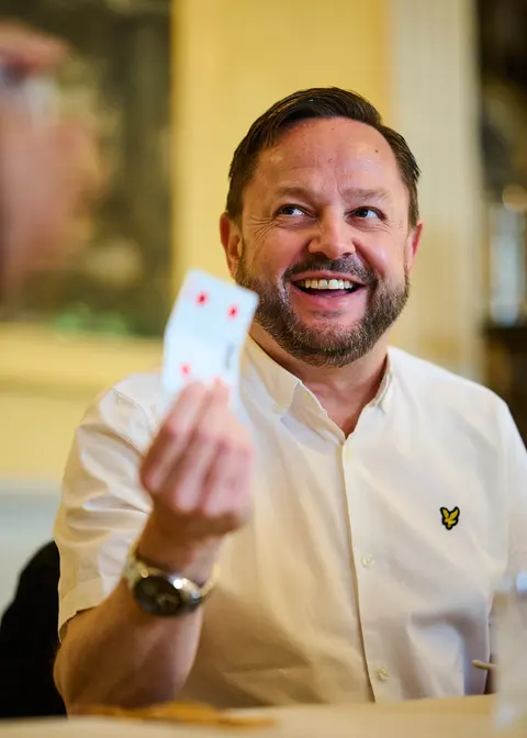 A guest holding up a playing card, black and white
