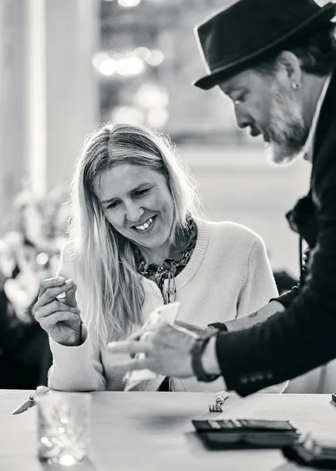 Two guests leaning in to talk at the table