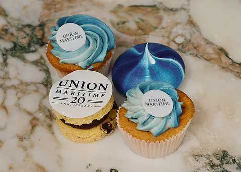 Blue iced Union Maritime anniversary cupcakes on marble