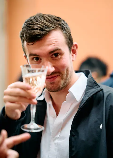 A guest raising a glass of champagne towards the camera