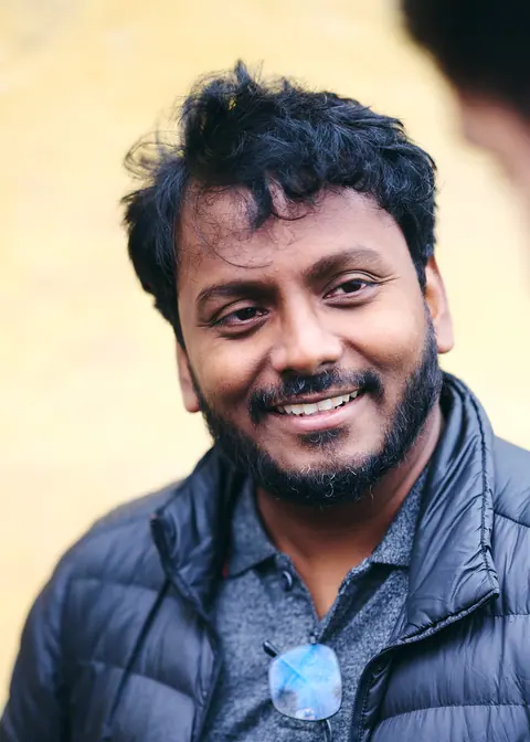 A guest smiling broadly against a warm stone wall