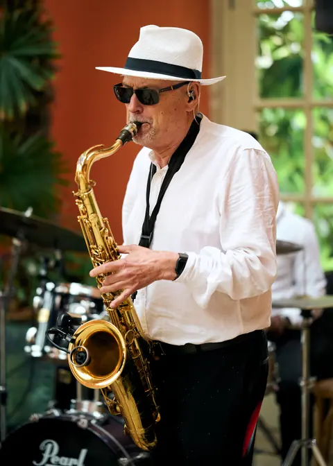 A saxophonist in a white hat and sunglasses playing